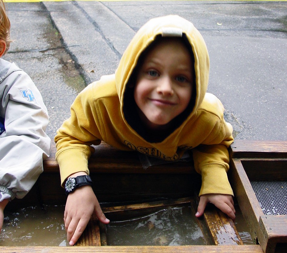 Kid in yellow hoodie sluicing for gems at a Wisconsin Destination